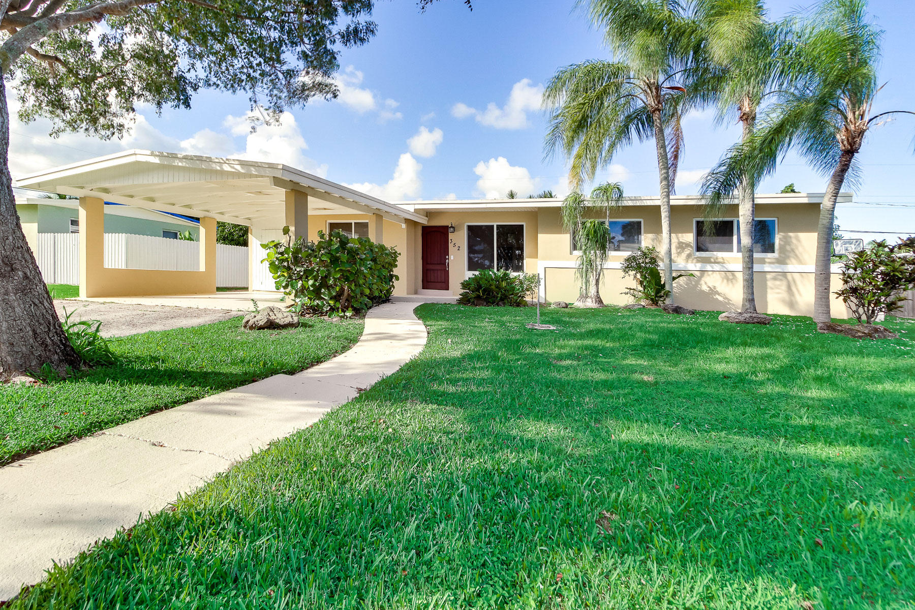352 East Lake Road Palm Springs, FL 33461 - Photo 1 of 31 a front view of a house with a yard and potted plants
