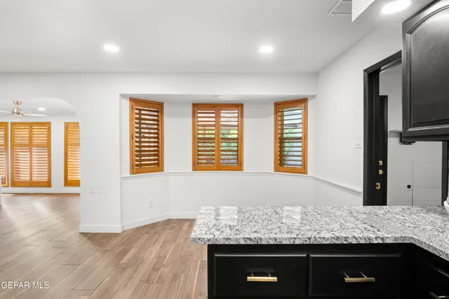 an empty room with wooden floor chandelier fan and windows