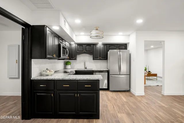 a living room with stainless steel appliances furniture and kitchen view