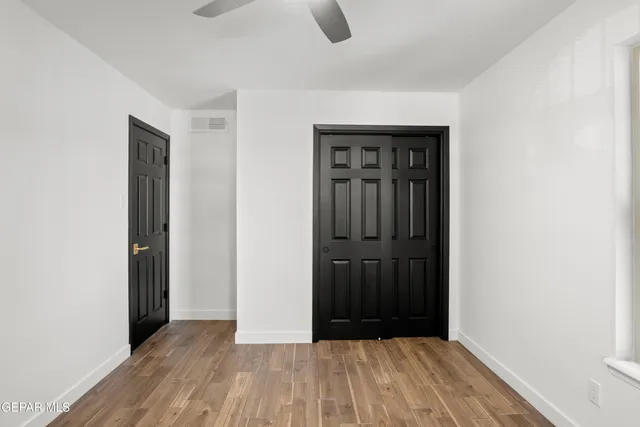 an empty room with wooden floor chandelier fan and windows