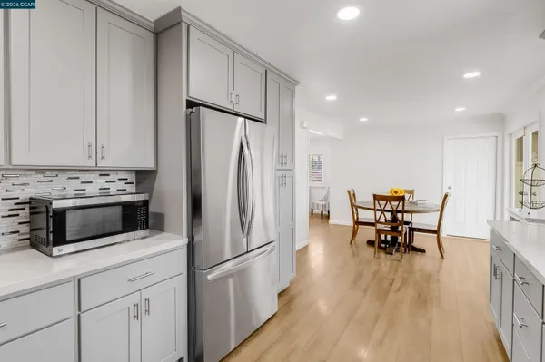 a kitchen with stainless steel appliances a refrigerator a stove a dining table and chairs with wooden floor