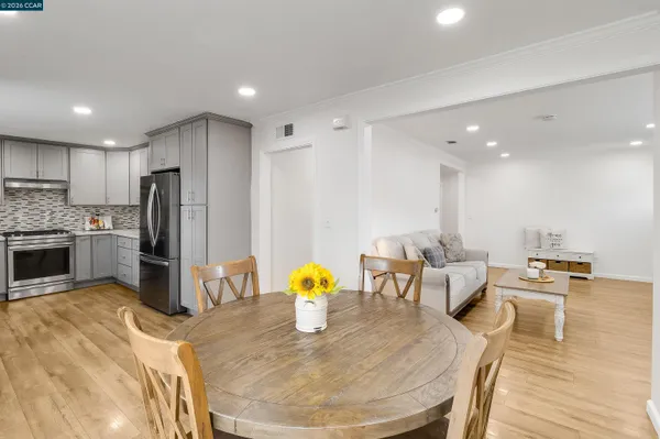 a kitchen with stainless steel appliances granite countertop a sink a stove a dining table and chairs