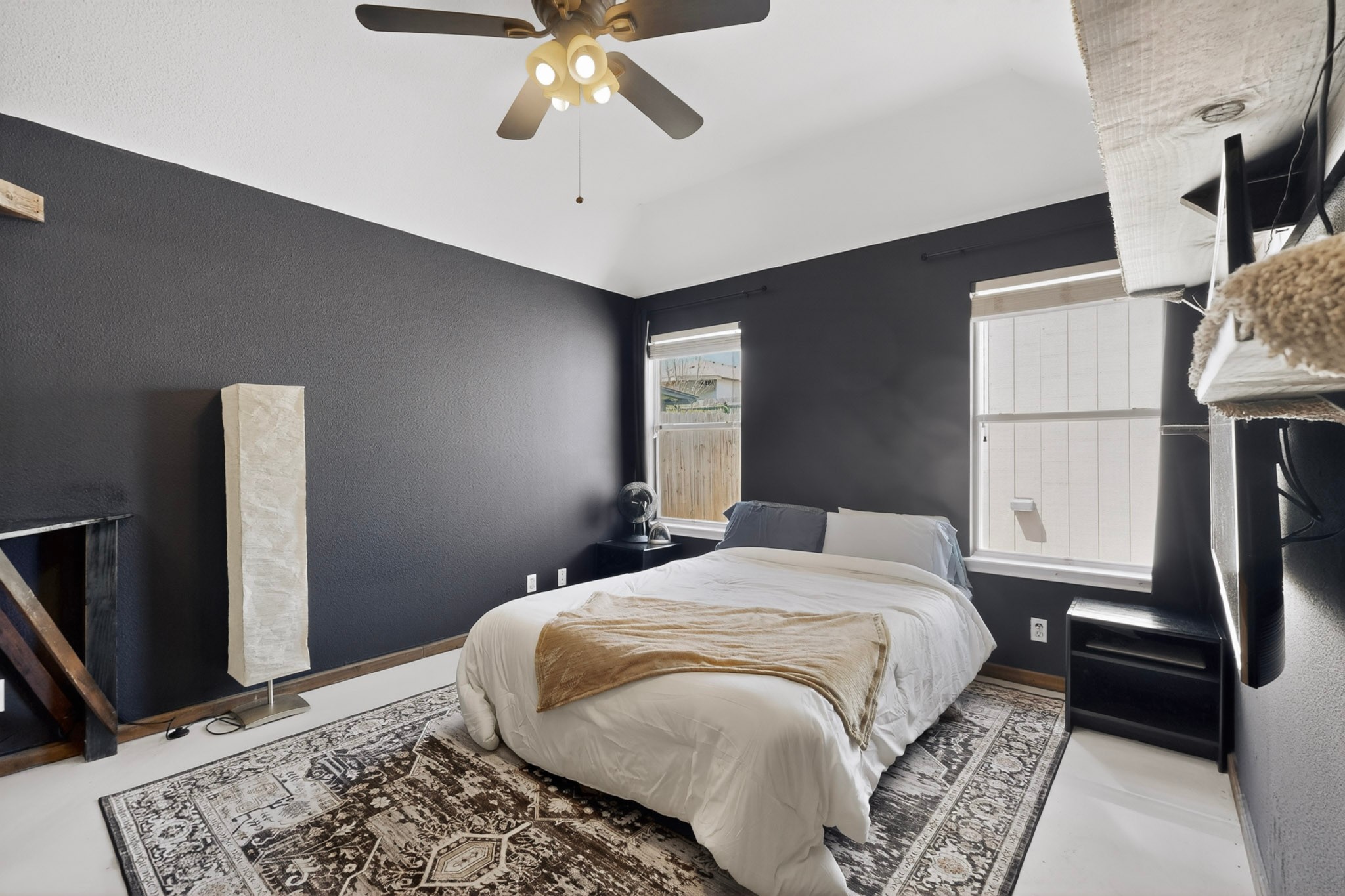 15104 Mimebark Way Austin, TX 78724 - Photo 17 of 38 Vaulted ceiling bedroom featuring two windows, a ceiling fan with integrated lighting, and dark accent walls