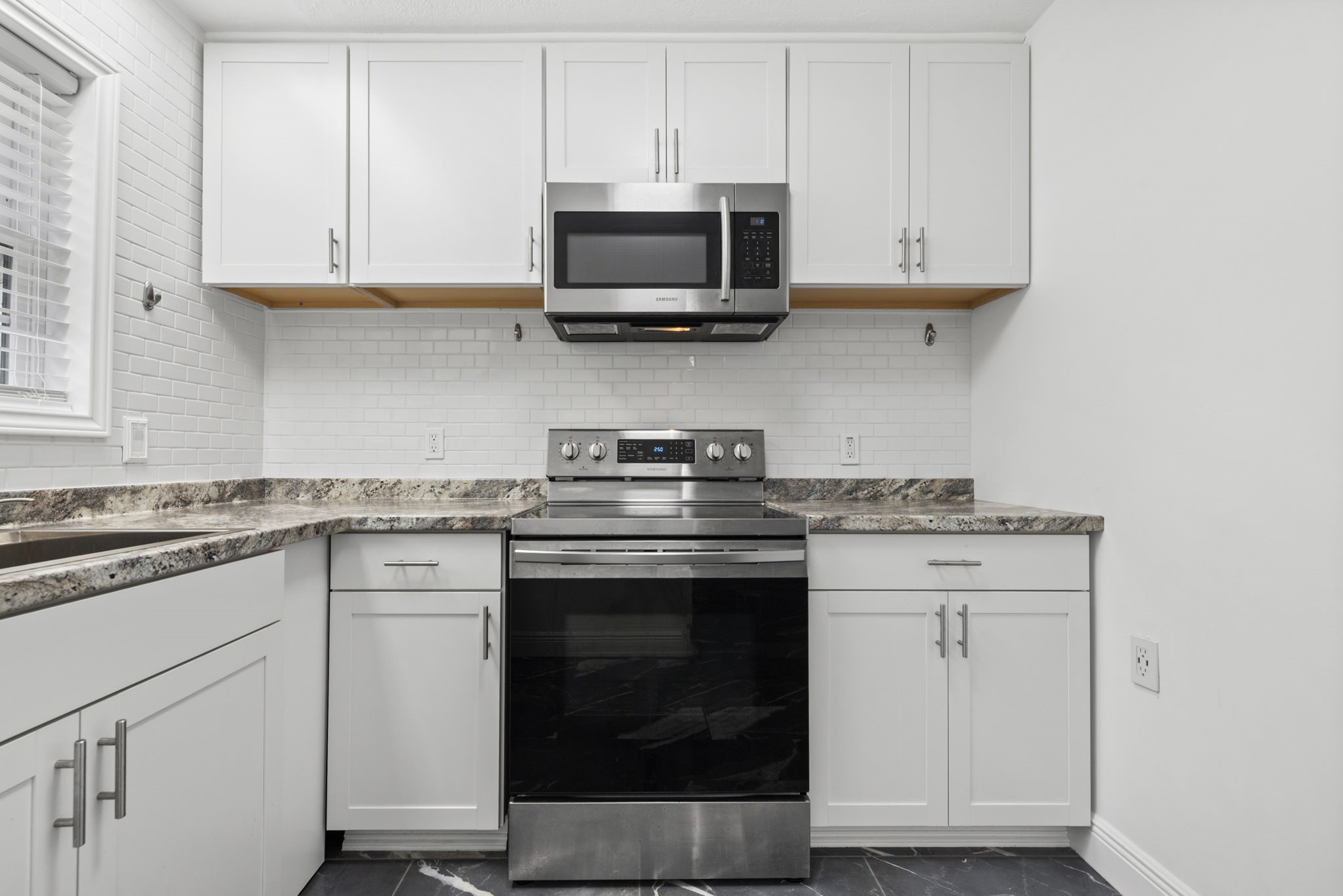 7900 Westheimer Road, Unit 121 Houston, TX 77063 - Photo 14 of 23 Modern kitchen with sleek stainless steel appliances, white cabinetry, and elegant marble countertops.