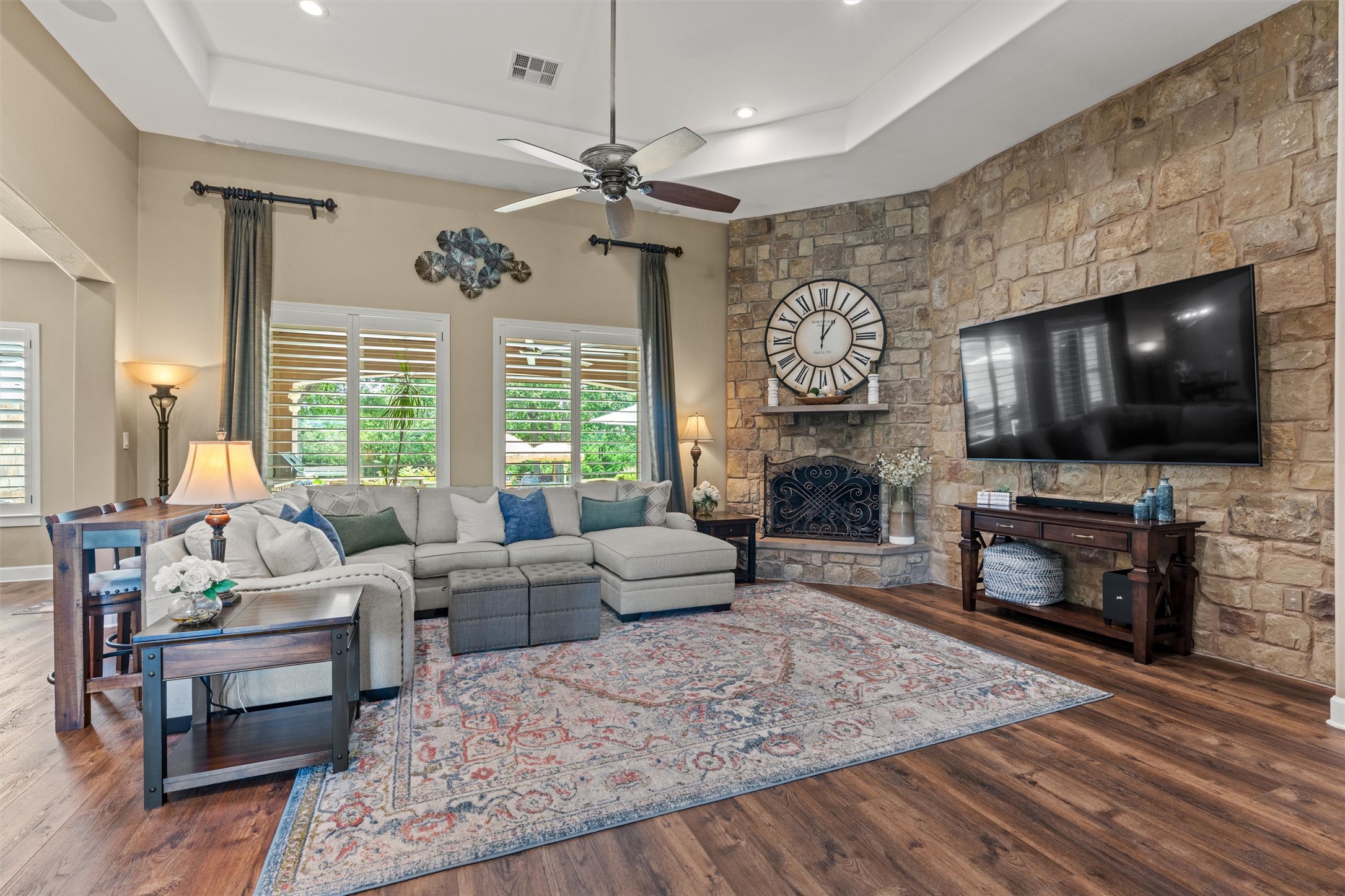 104 Adobe Cove Georgetown, TX 78633 - Photo 7 of 40 A spacious living room features rich wood flooring, a stone fireplace, and a tray ceiling.
