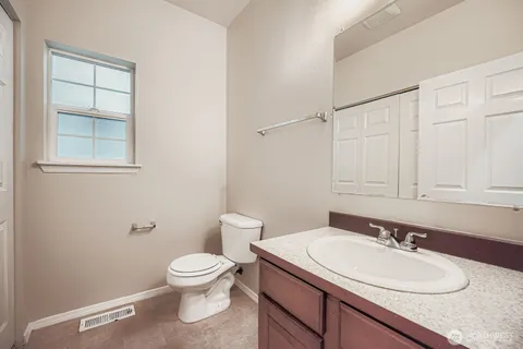 a bathroom with a granite countertop sink a toilet and a mirror