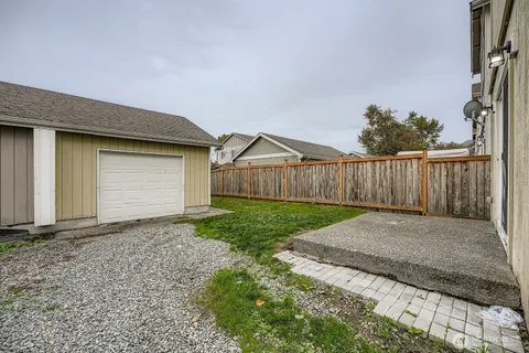 a view of backyard of house with wooden fence