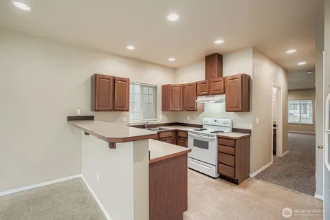 a kitchen with stainless steel appliances granite countertop a stove top oven a sink and a refrigerator