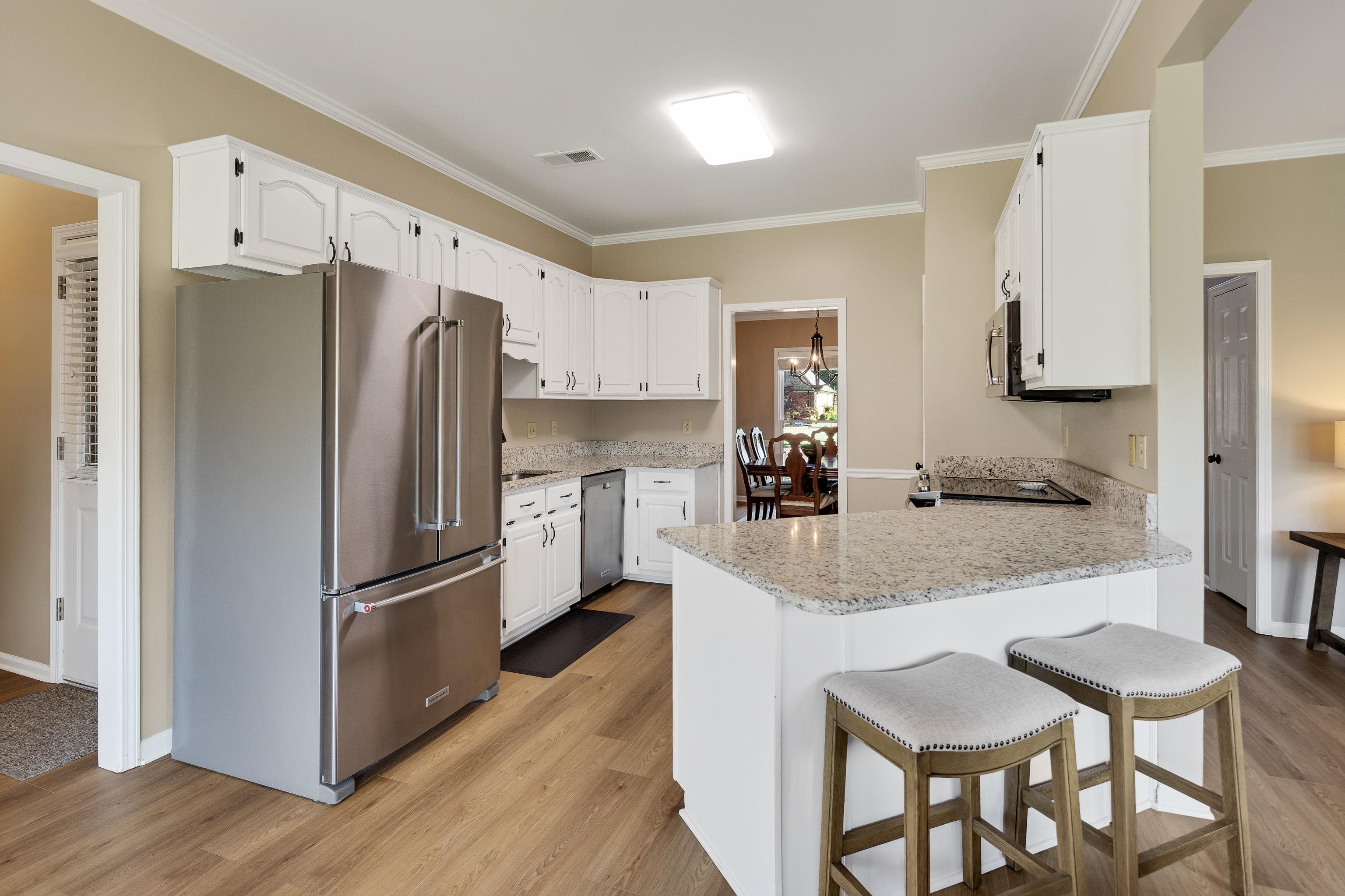 540 Whitney Way Collierville, TN 38017 - Photo 8 of 22 Kitchen with stainless steel appliances, a peninsula, a breakfast bar, light wood-style floors, and white cabinets
