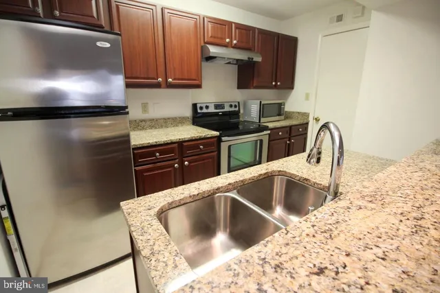 a kitchen with granite countertop a refrigerator and a sink