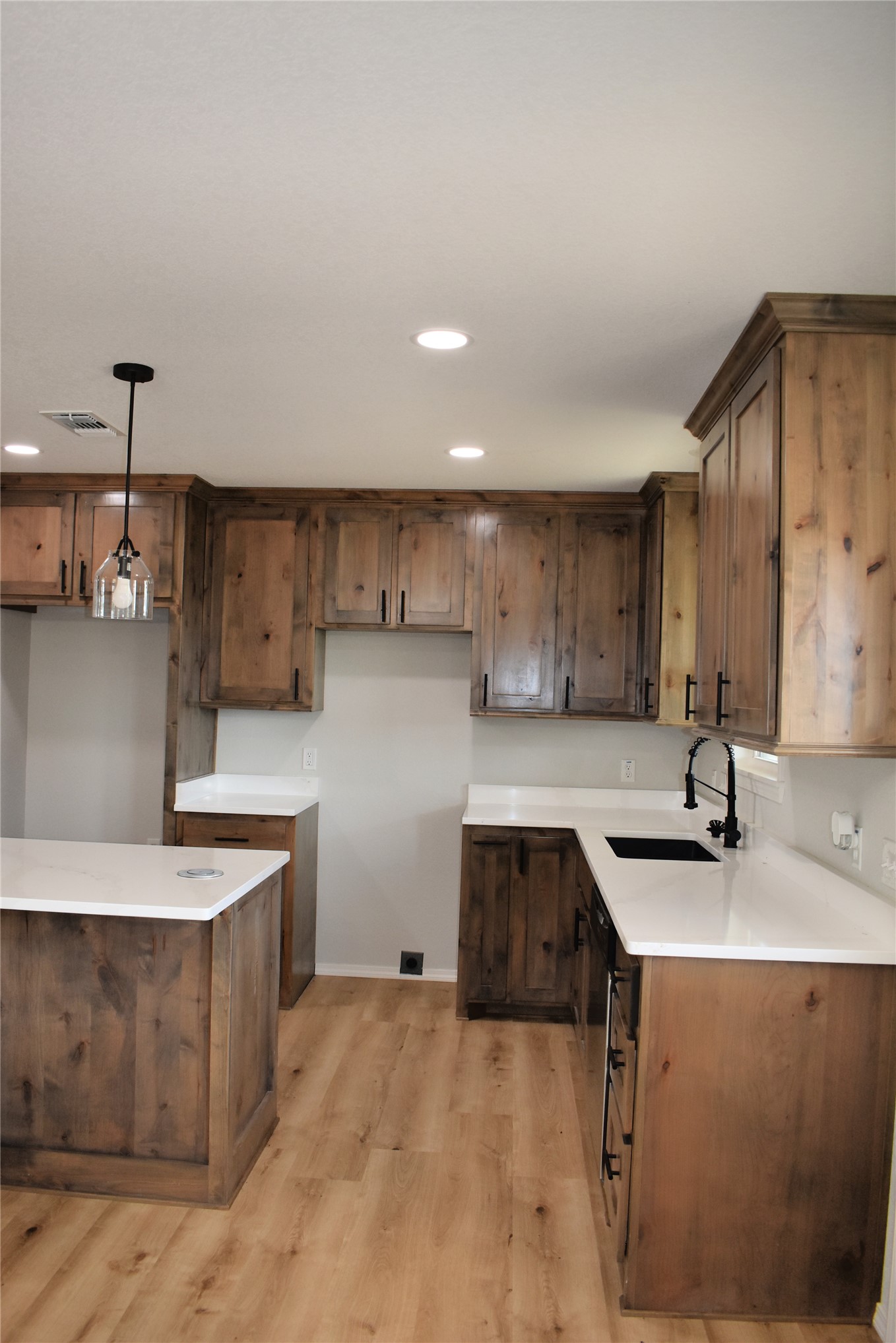 2915 East 2090 Road Hugo, OK 74743 - Photo 6 of 27 Kitchen featuring wood-finish cabinetry, light-toned countertops, a central island, wood-finish flooring, and recessed lighting