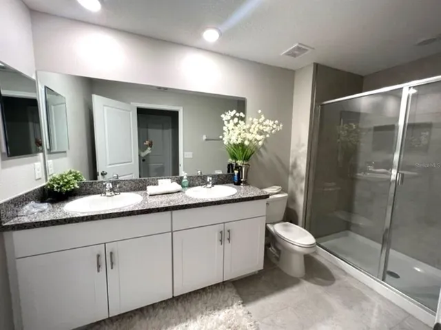 a bathroom with a double vanity sink toilet and shower