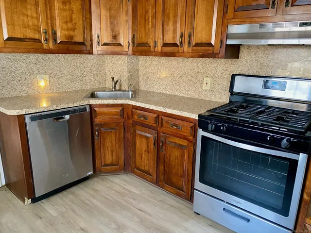 a kitchen with stainless steel appliances wooden cabinets and a stove top oven