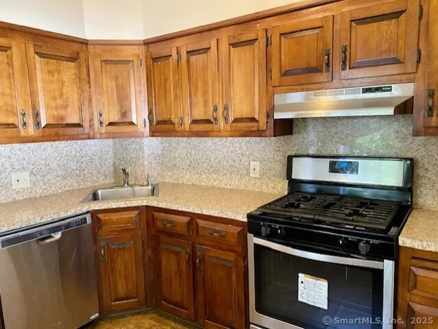 a kitchen with stainless steel appliances a stove a sink and cabinets