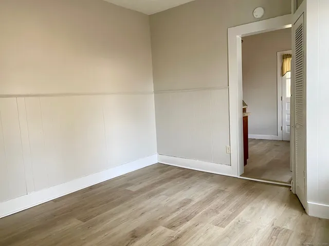 an empty room with wooden floor and mirror