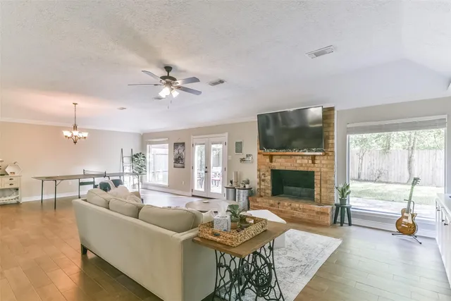 a living room with furniture a fireplace a flat screen tv and a large window