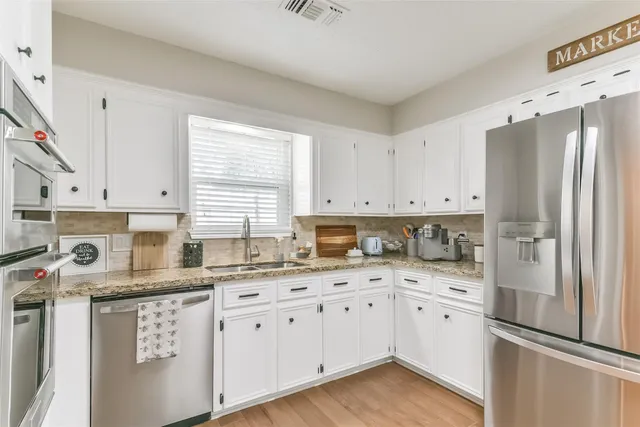 a kitchen with stainless steel appliances granite countertop a refrigerator sink and cabinets