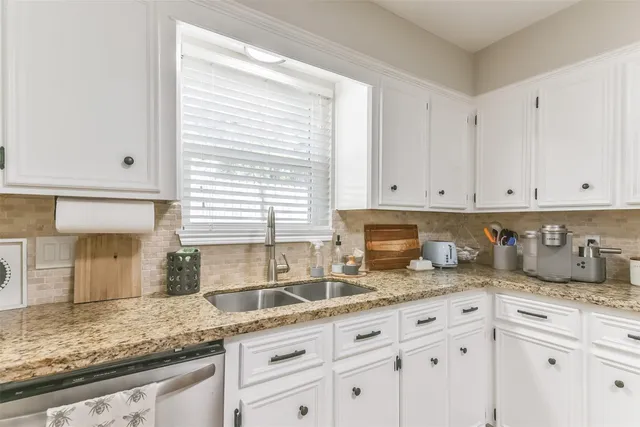 a kitchen with granite countertop white cabinets and a window