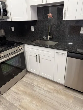 a kitchen with granite countertop white cabinets and black appliances