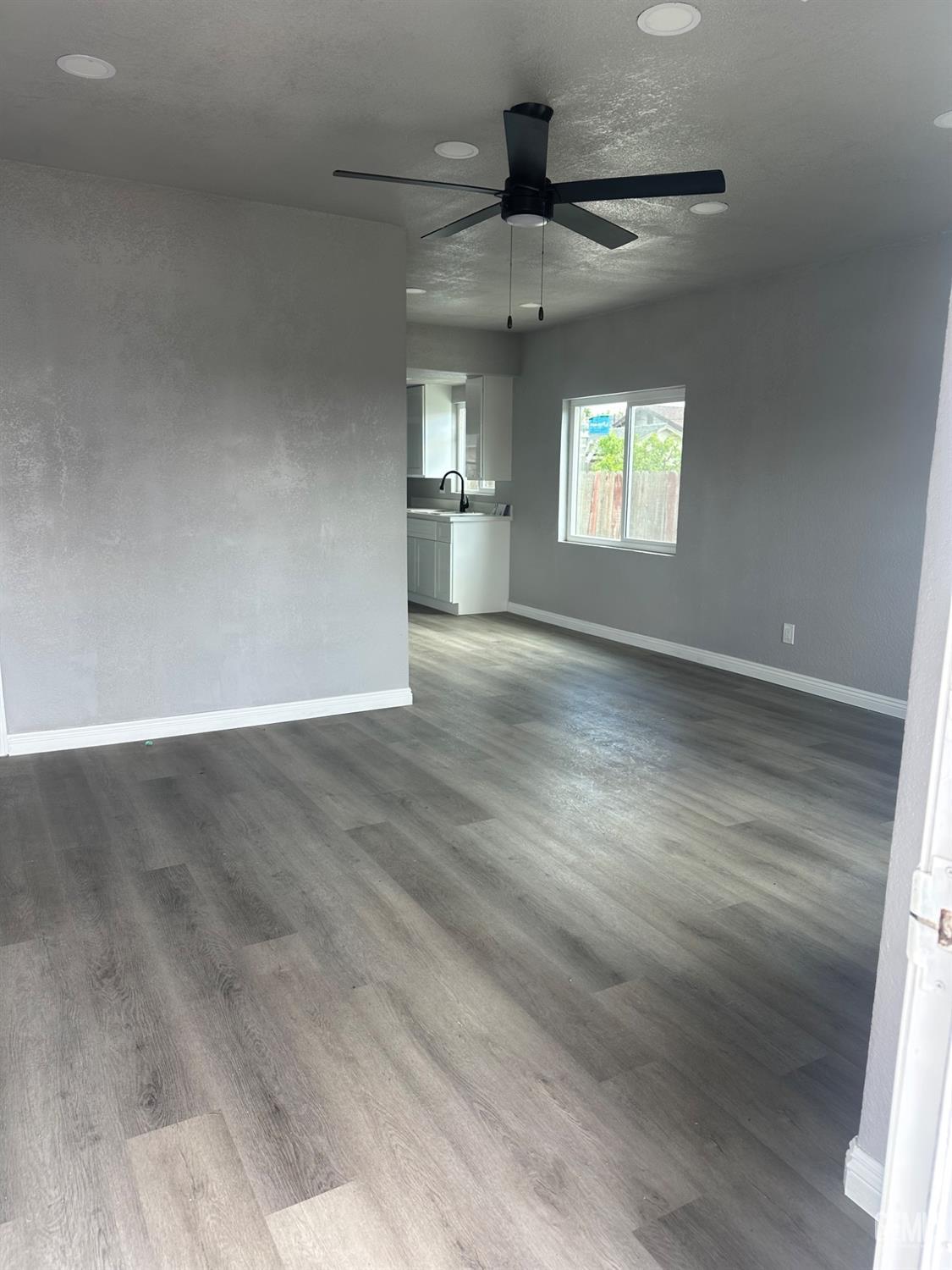 Undisclosed Address Delano, CA 93215 - Photo 3 of 13 an empty room with wooden floor and windows