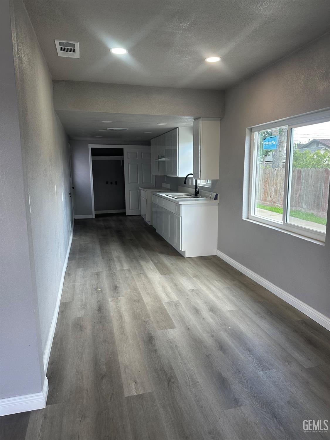 Undisclosed Address Delano, CA 93215 - Photo 4 of 13 an empty room with wooden floor and windows