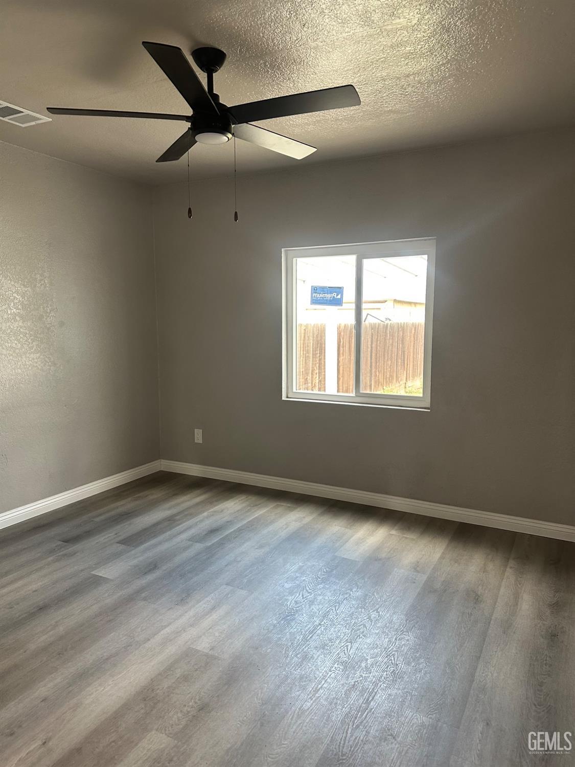Undisclosed Address Delano, CA 93215 - Photo 5 of 13 an empty room with wooden floor fan and windows