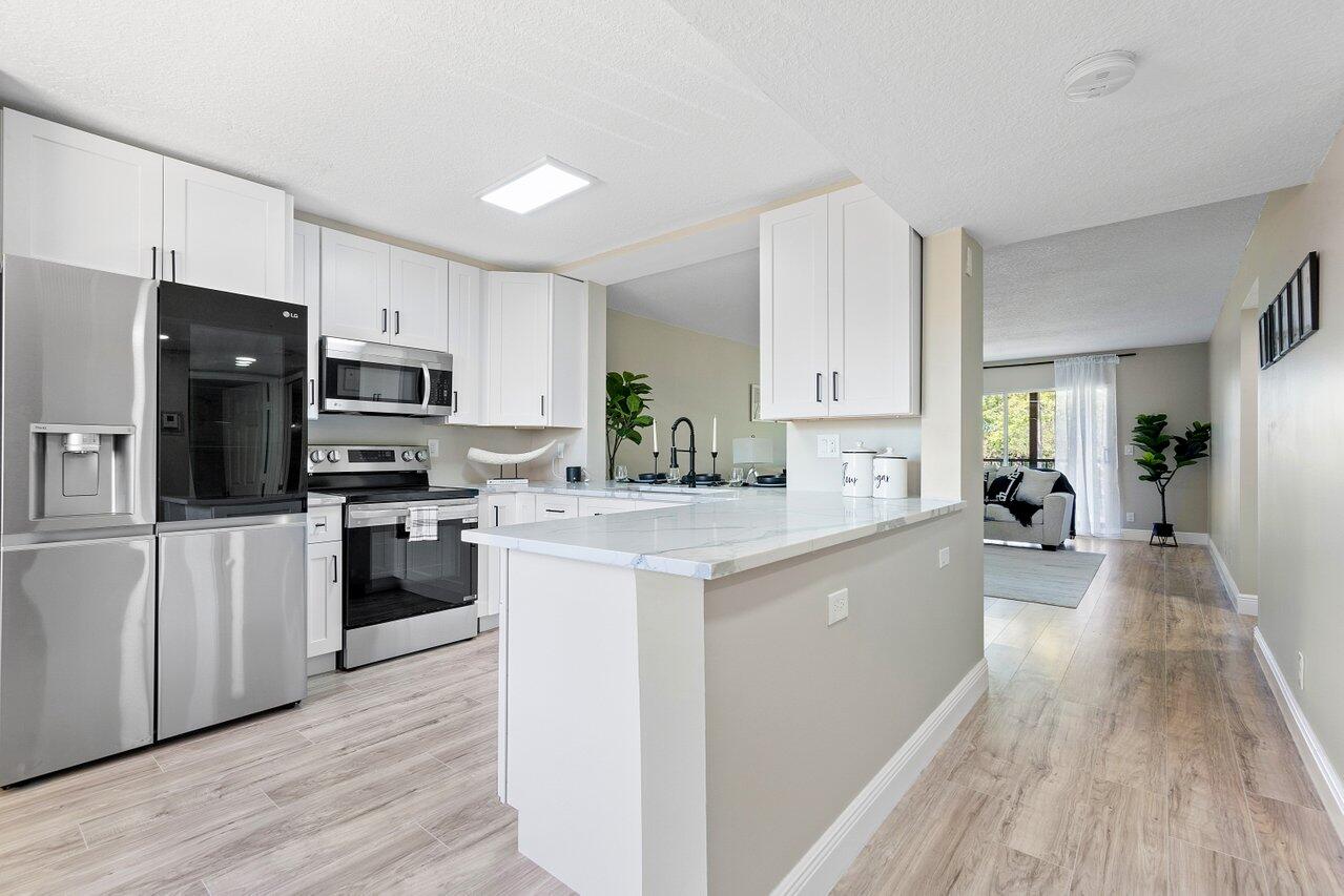 a large kitchen with cabinets wooden floor and stainless steel appliances