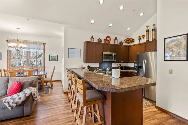 a living room with stainless steel appliances furniture a dining table and a chandelier