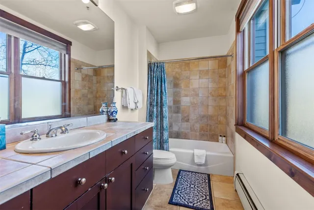 a bathroom with a granite countertop sink a mirror a bathtub and next to a window