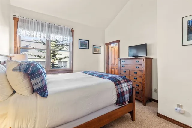 a bedroom with a bed and a flat tv screen on dresser