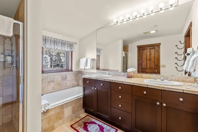 a bathroom with a granite countertop double vanity sink a mirror and a bathtub