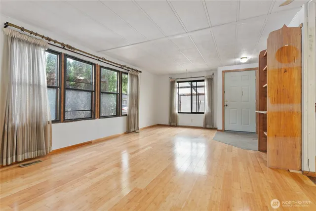 a view of an empty room with window and wooden floor