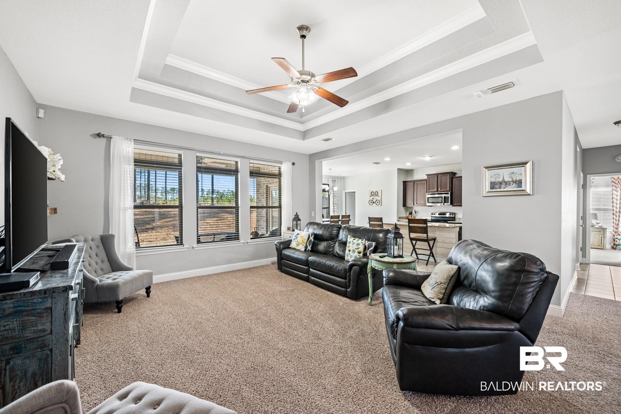 31472 Hoot Owl Road Daphne, AL 36527 - Photo 6 of 32 Living room with ceiling fan, ornamental molding, light carpet, and a tray ceiling