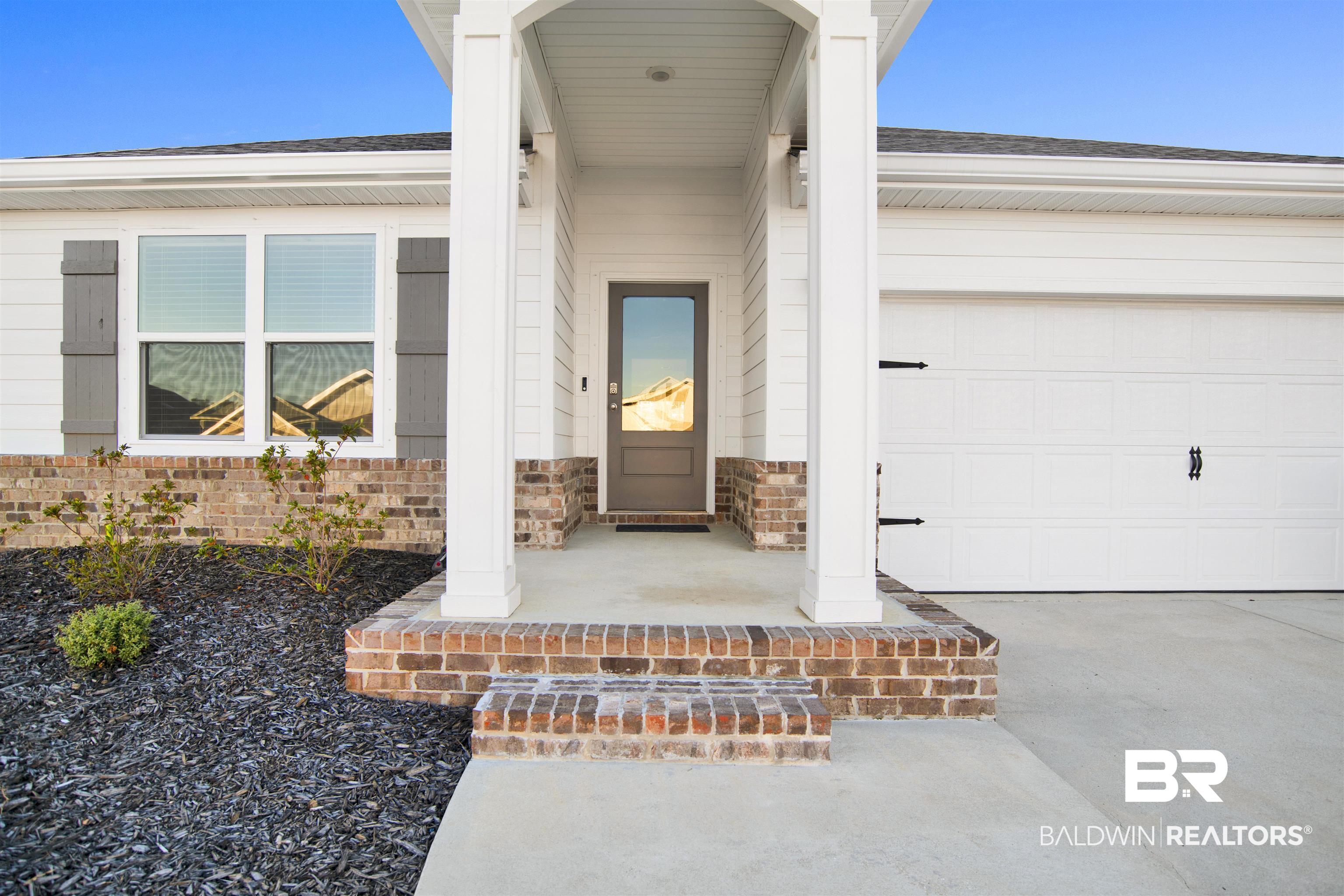 32038 Lyon Road Daphne, AL 36527 - Photo 5 of 30 Entrance to property featuring covered porch, brick siding, a shingled roof, and an attached garage