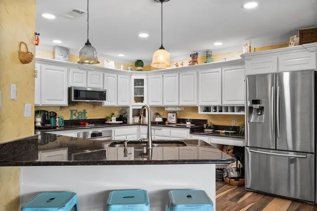 a kitchen with stainless steel appliances granite countertop a refrigerator a stove top oven a sink and dishwasher