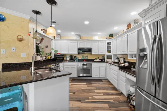 a kitchen with stainless steel appliances granite countertop a refrigerator a stove top oven a sink dishwasher and white cabinets