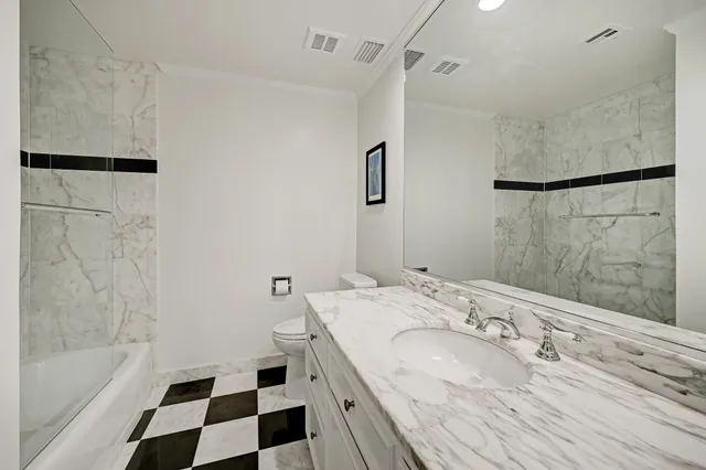 a bathroom with a granite countertop sink a toilet a shower and a mirror