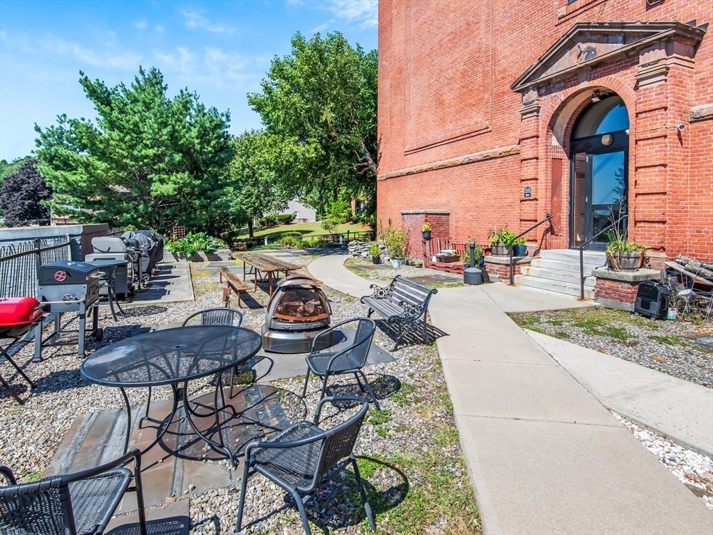 28 Adams Street, Unit 102 Worcester, MA 01604 - Photo 29 of 34 a view of a patio with table and chairs potted plants and palm tree