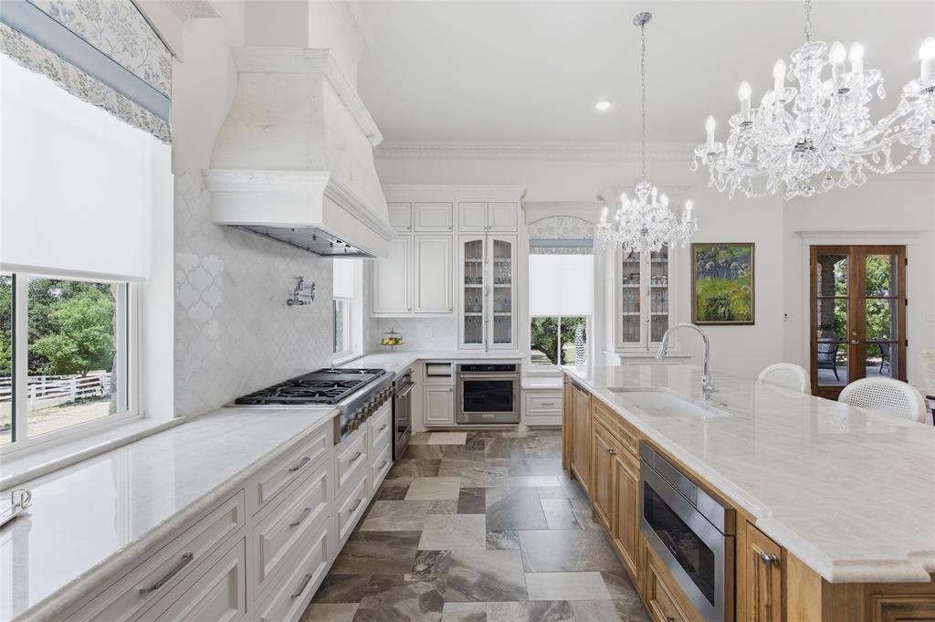 501 Upper Denton Road Weatherford, TX 76085 - Photo 12 of 40 Gourmet kitchen featuring a built-in range, custom cabinetry, large central island, overhead crystal chandeliers, and patterned tile flooring