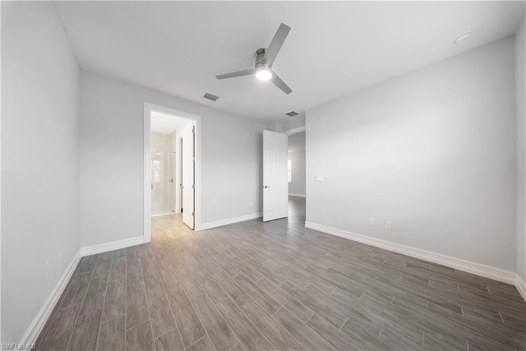 1059 Enbrook Loop Naples, FL 34114 - Photo 11 of 40 Unfurnished bedroom featuring wood tiled floors, ceiling fan, and connected bathroom