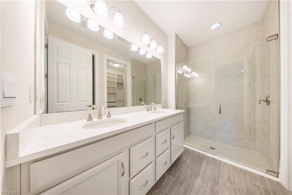 1059 Enbrook Loop Naples, FL 34114 - Photo 15 of 40 Bathroom with double vanity, a stall shower, a walk in closet, and wood tiled floors