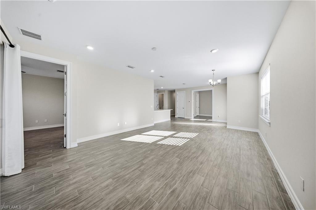 1059 Enbrook Loop Naples, FL 34114 - Photo 17 of 40 Unfurnished room with dark wood finished floors and a chandelier