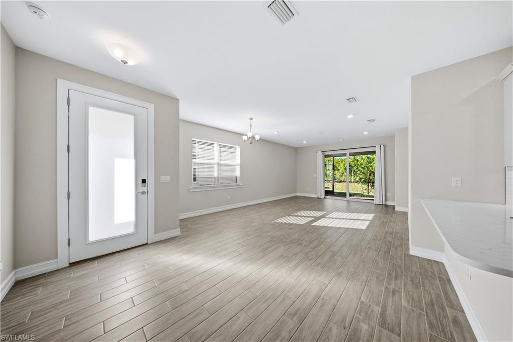 1059 Enbrook Loop Naples, FL 34114 - Photo 4 of 40 Empty room with a chandelier, wood finish floors, and healthy amount of natural light