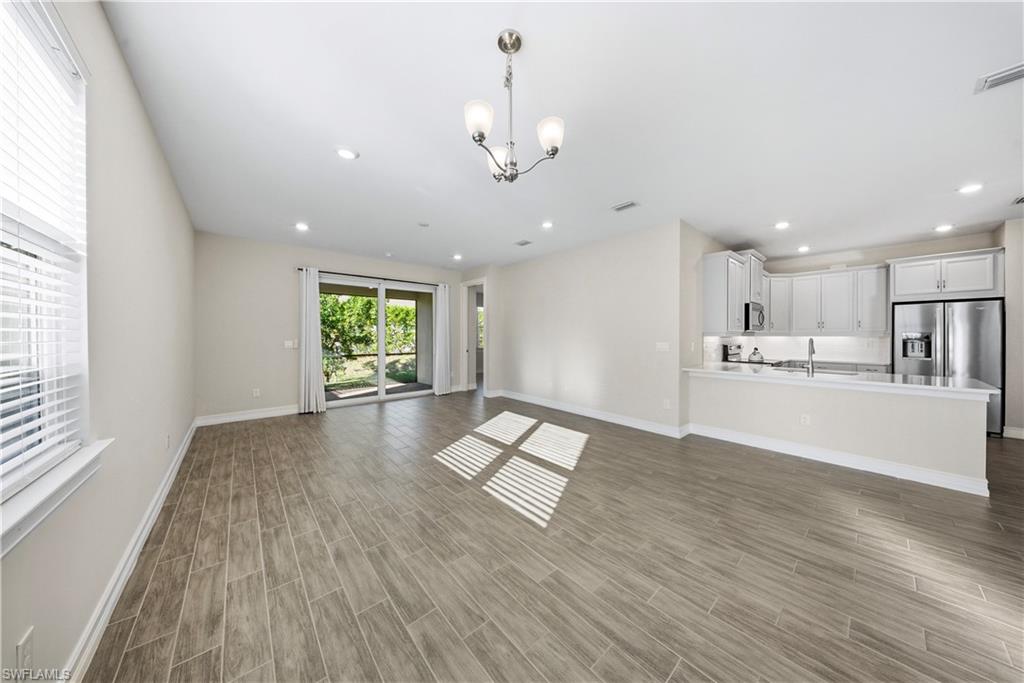 1059 Enbrook Loop Naples, FL 34114 - Photo 6 of 40 Unfurnished living room with wood finish floors and hanging lights