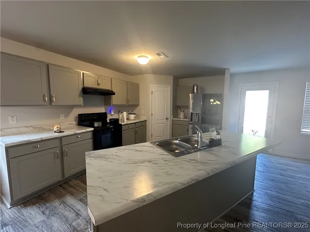 a kitchen with kitchen island granite countertop a sink appliances and cabinets