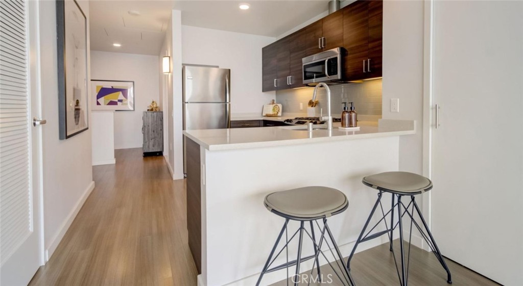 100 Van Ness Avenue, Unit 402 San Francisco, CA 94102 - Photo 11 of 75 a kitchen with stainless steel appliances a refrigerator a stove a sink a microwave and island with wooden floor