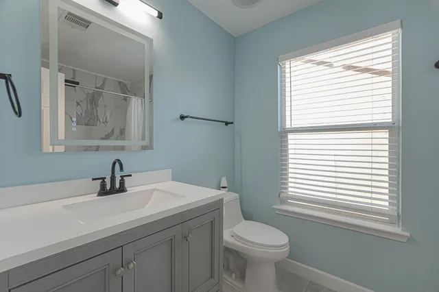 a bathroom with a sink a toilet and a window