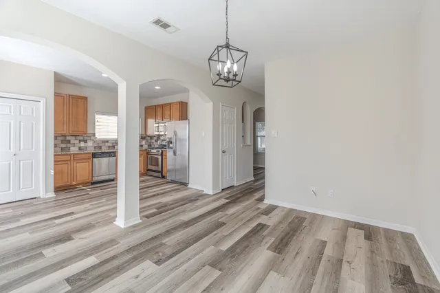 a view of a room with wooden floor staircase and kitchen view