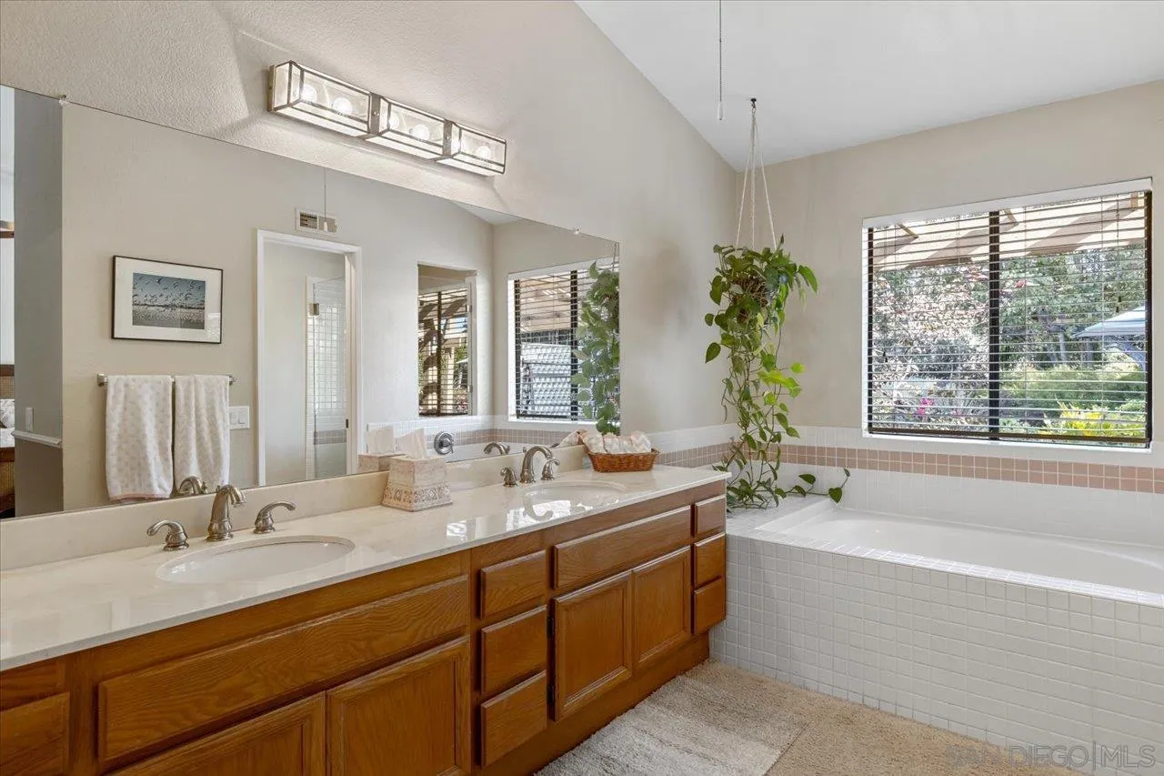 1787 Wolverine Way Vista, CA 92084 - Photo 19 of 35 a bathroom with double vanity sinks a large mirror and a bathtub