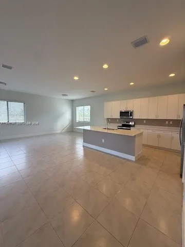 a open kitchen with kitchen island white cabinets and stainless steel appliances